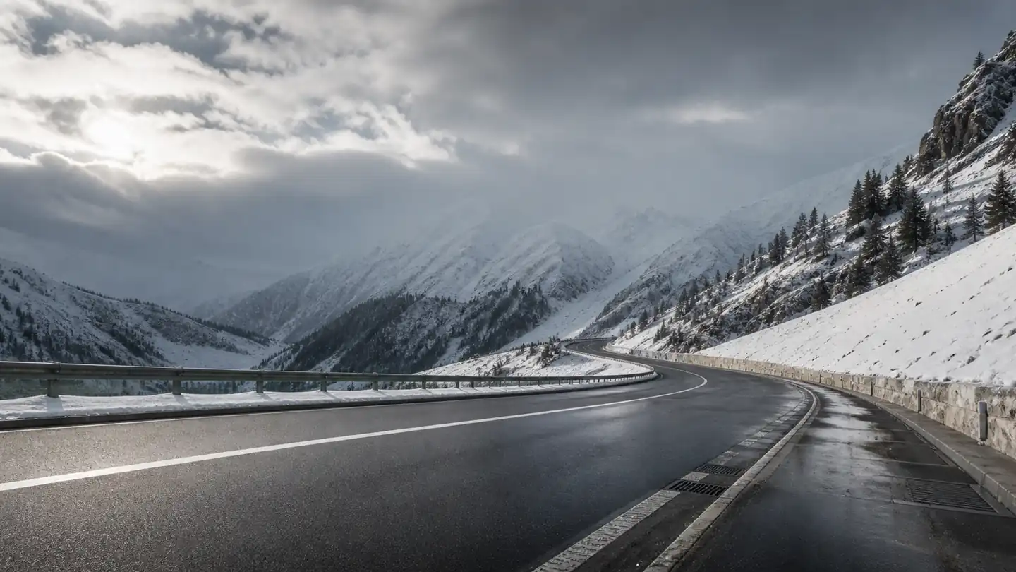 Pusta alpejska droga przechodząca z mokrego asfaltu w lekką śnieżycę - Dunlop SP Winter Sport 3D przez zmienną górską zimę