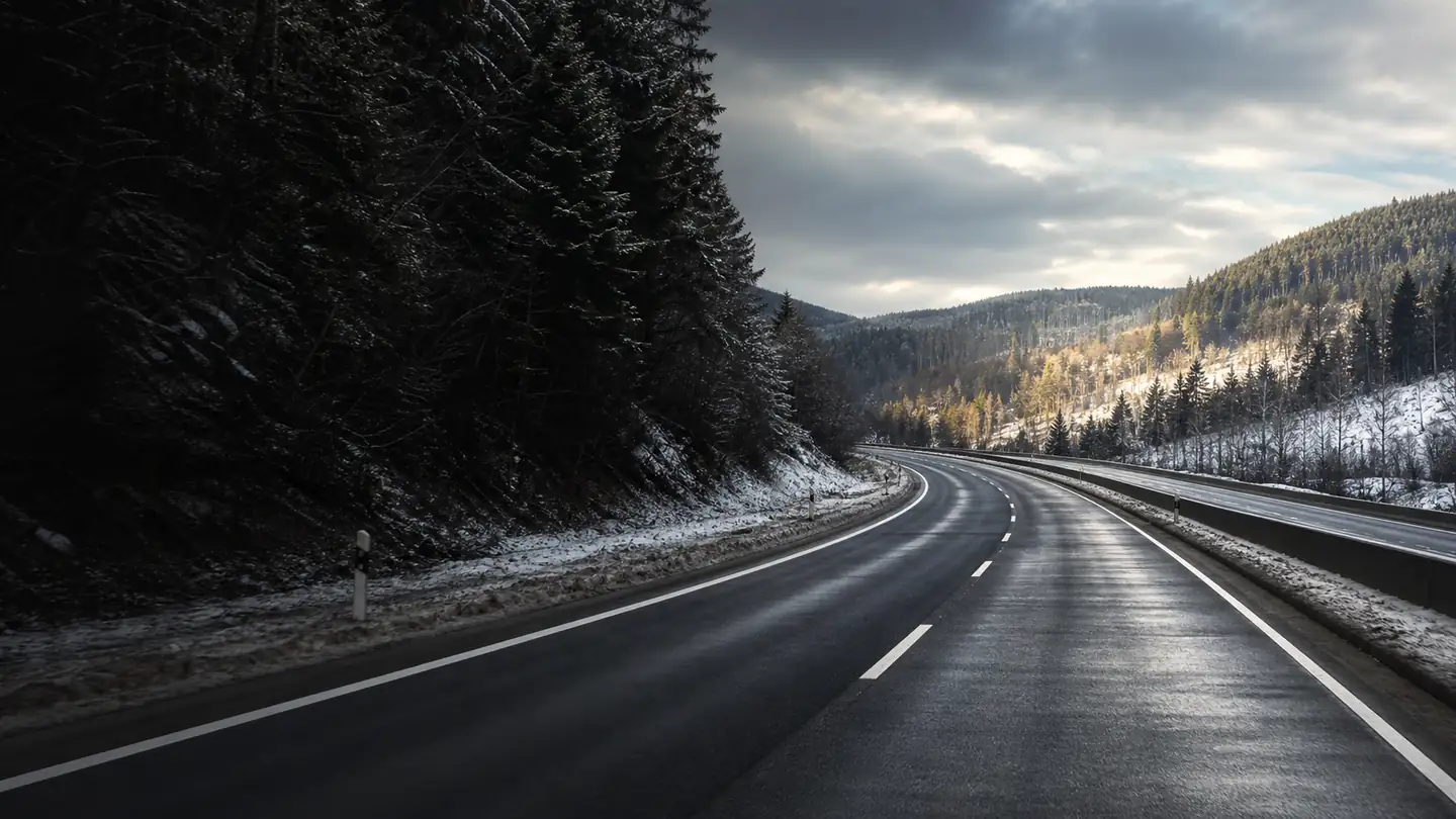Pusta mokra droga przez niskie ośnieżone wzgórza podczas zimowego przejaśnienia - Falken EuroAll Season AS220 Pro od mokrego łuku po śnieżną trasę