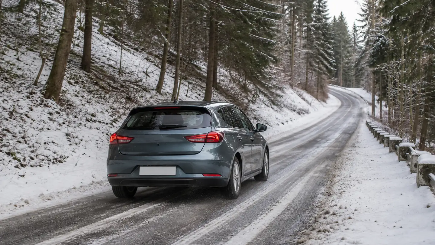 Grafitowy hatchback na częściowo odśnieżonej leśnej drodze zimą - Kleber Krisalp HP3 na śnieżną i mokrą zimową drogę