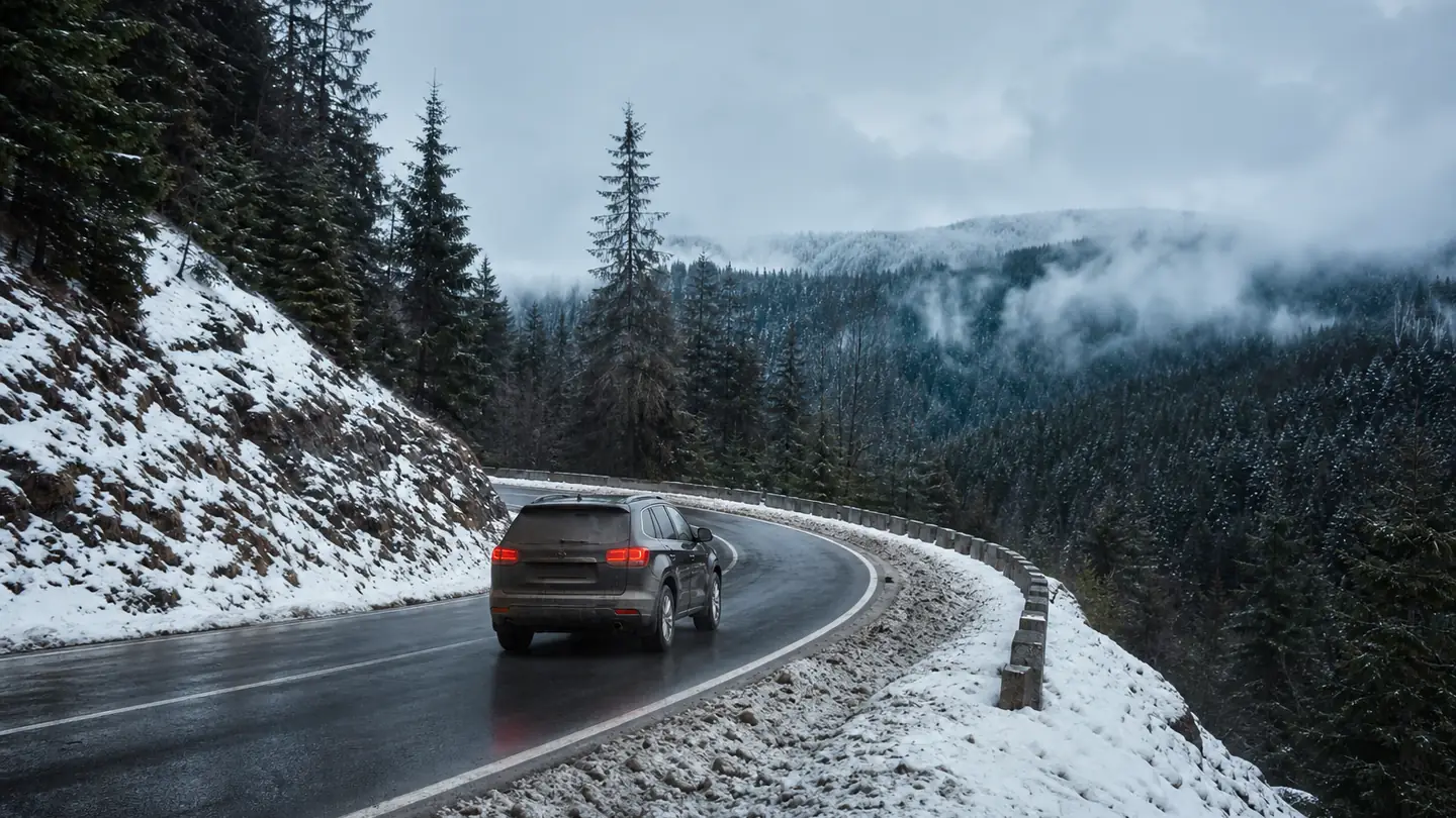 Ciemny SUV na mokrym górskim zakręcie z błotem pośniegowym przy poboczu - Kumho WinterCraft SUV WS71 na mokry śnieg i zimowy podjazd