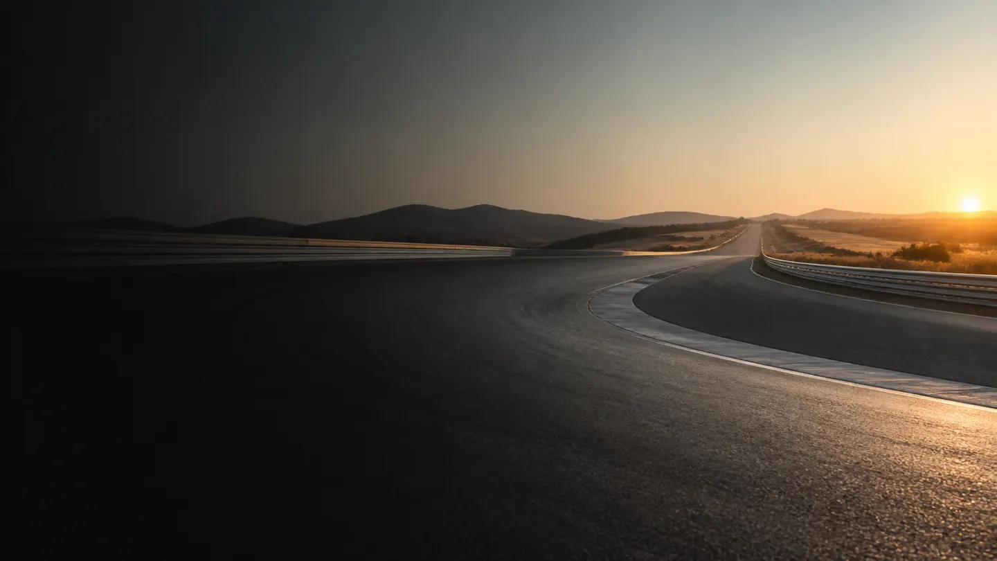 Pusty szeroki łuk nowoczesnego toru testowego o letnim wschodzie słońca - Michelin Pilot Super Sport między drogą a zamkniętym torem
