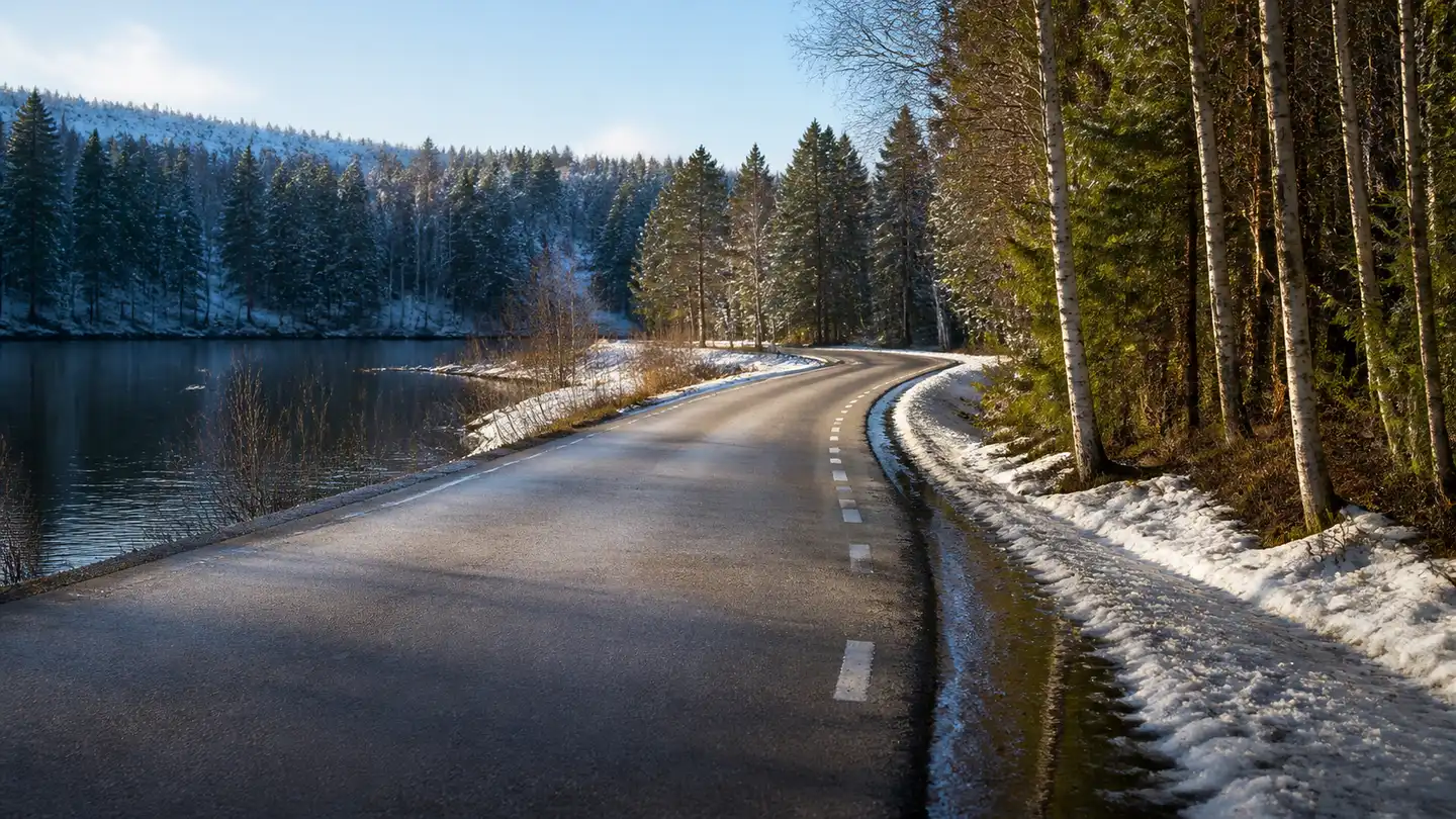 Pusta północna droga nad jeziorem podczas odwilży z wodą i śniegiem na poboczu - Nokian Seasonproof 1 od letniego deszczu po zimową odwilż